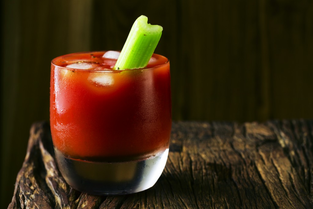 A bloody mary cocktail sitting on a rustic wooden bar.