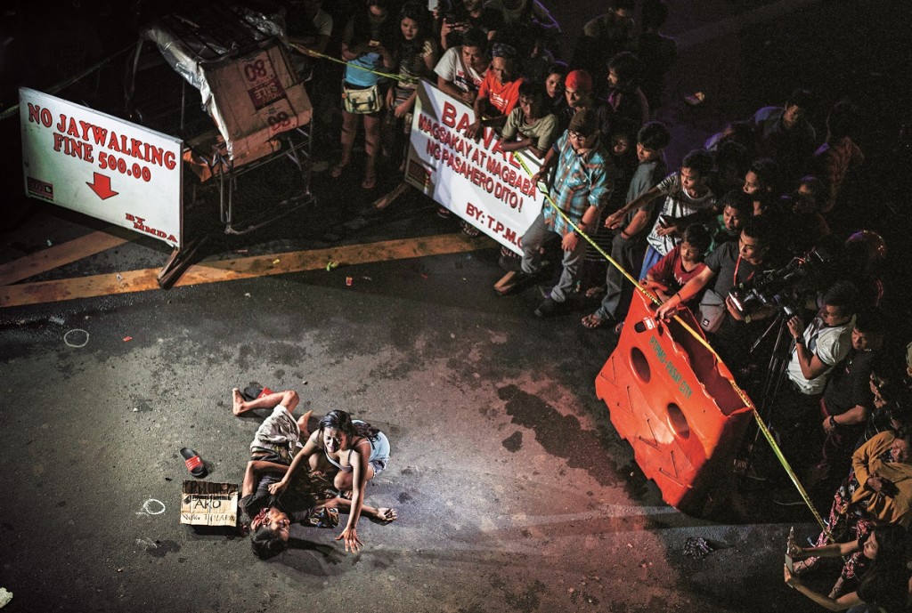 This photo taken on July 23, 2016 shows Jennilyn Olayres (centre R) grieving beside the dead body of her partner Michael Siaron who was shot by unidentified gunman and left with a cardboard sign with a message "I'm a pusher" along a street in Manila. Hundreds of people have died since President Rodrigo Duterte won a landslide election in May, promising to rid society of drugs and crime in six months by killing tens of thousands of criminals. Police figures showed this week that 402 drug suspects had been killed a month into Duterte's presidency. This figure does not include those slain by suspected vigilantes. / AFP / NOEL CELIS / TO GO WITH Philippines-crime-drugs-rights,FOCUS by Noel Celis (Photo credit should read NOEL CELIS/AFP/Getty Images)