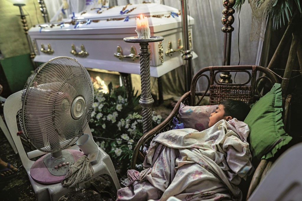 A boy sleeps next to the coffin of Ricardo Delemon, who was shot by unidentified gunmen in a drug-related vigilante killing, at his wake in Manila, Philippines, August 11, 2016. Nearly 1,000 people have been killed by police or vigilantes in the Philippines as President Rodrigo Duterte ramps up his campaign against illegal drugs. Duterte has publicly named hundreds of politicians, military and police personnel, and other influential people allegedly involved in the drug trade and has ordered them to surrender or be hunted down. Duterte won the presidency two months ago by pledging to kill thousands in an all-out war against drugs in a country where drugs and crime are deeply-rooted. (Photo by Zeke Jacobs/NurPhoto via Getty Images)