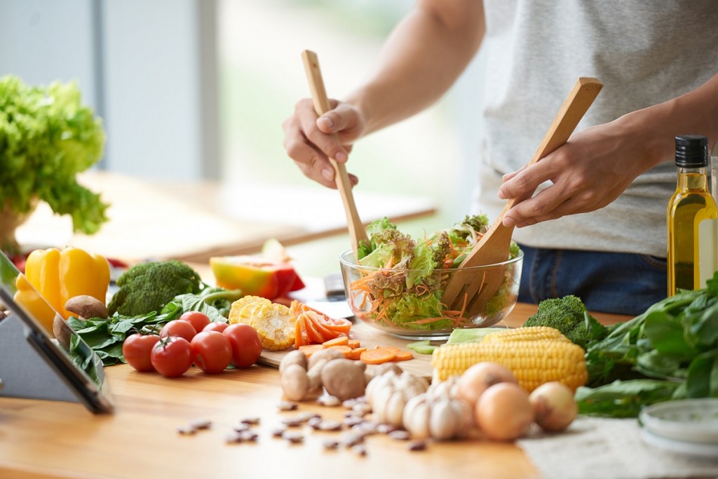 Vegetarian man mixing vegetable salad in bowl