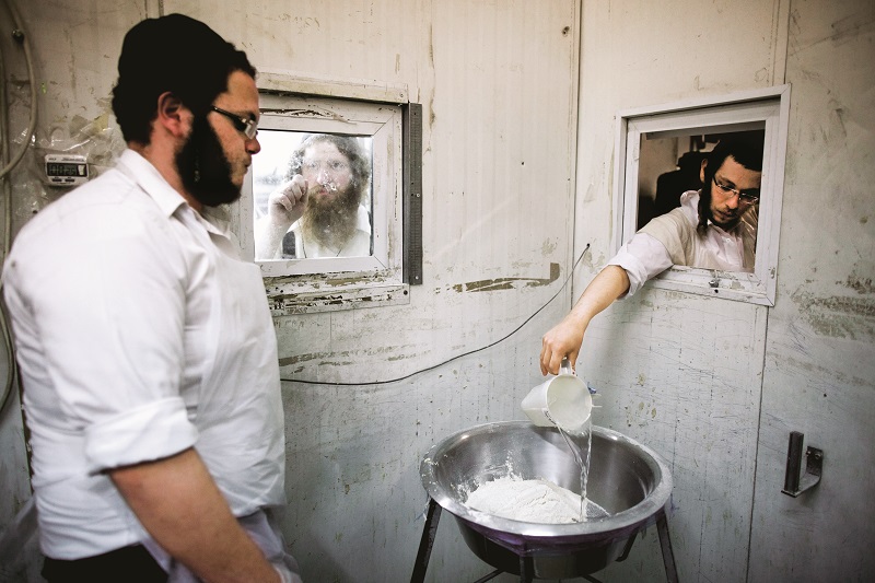 MIDEAST ISRAEL PASSOVER.jpg:epa05265485 Ultra-Orthodox Jews in a sterile room pour water into a bowl from a small window at a Matzah bakery in the southern Israeli city of Ashdod, Israel, 18 April 2016. Matzah, or unleavened bread, is used instead of bread during the week-long Jewish holiday of Passover, commemorating the Jewish exodus from Egypt in Biblical times. EPA/ABIR SULTAN