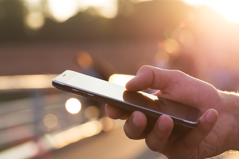 Man using his Mobile Phone outdoor, close up