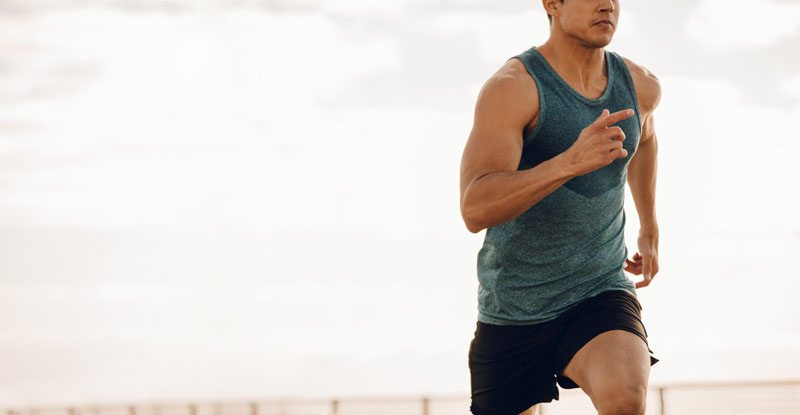 HMADPT Cropped shot of young man running along a seaside promenade. Healthy young male runner working out on a road by the sea.