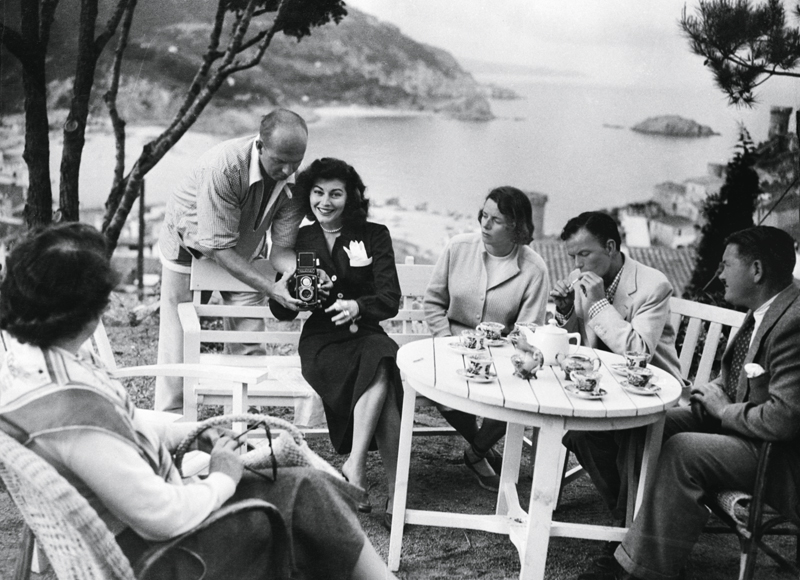 (Original Caption) 11/1956-Costa Brava, Spain: When Frank Sinatra heard of romance brewing between Ava Gardner and Mario Cabre in 1950, he rushed over to Spain with a bagful of jewels to woo Ava back. Here they are sitting in a garden overlooking the beautiful Costa Brava. Sinatra, second from right, chain smokes...