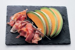 Close-Up Of Meat With Cantaloupe Slices On Cutting Board